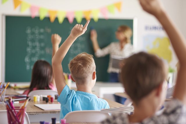 schools Children raising hands in classroom