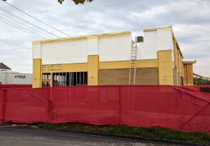 Yellow and white building under construction with red fence