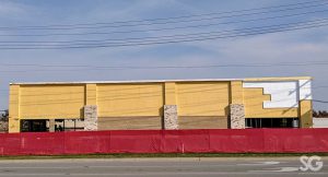 yellow building under construction with a red fence around it