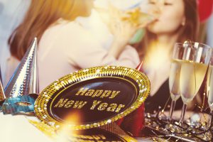 celebrate: a happy new year sign with two girls sipping champagne in the background
