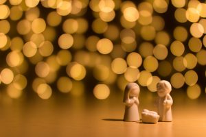 church: 3 wooden figures to create a nativity scene with white blurry lights in the background