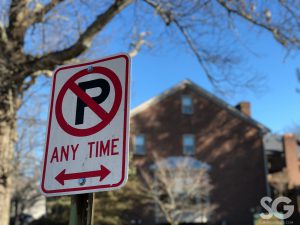 street sign that says no parking with a blurry building in the background