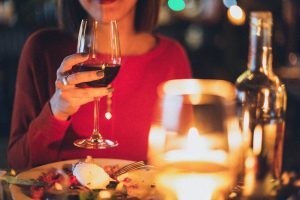 woman in a red dress holding a glass of wine with dinner