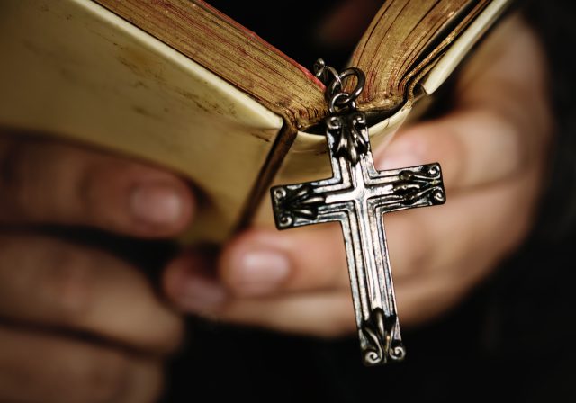 Easter Service: man holding a bible with a metal cross hanging