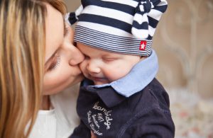 Mother's Day: woman giving her baby boy a kiss on the cheek