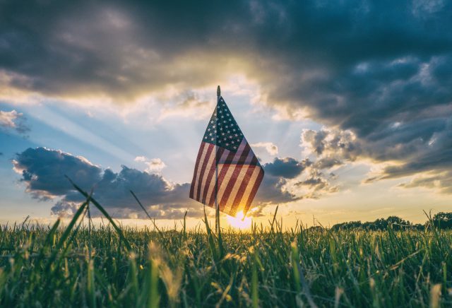 Memorial Day: flag in the grass with a sunset behind