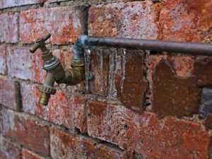pipes: a pipe with icycles hanging from it against a brick wall